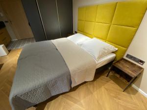 sypialnia z dużym łóżkiem z żółtym zagłówkiem w obiekcie Apartament Wrocław Marina nad Odrą 7 we Wrocławiu