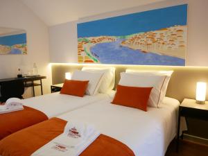 two beds in a hotel room with a painting on the wall at Serra do Pilar Porto Suites in Vila Nova de Gaia