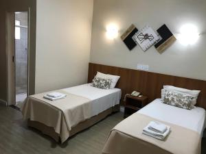 a hotel room with two beds and a mirror at Hotel Portal das Águas in Jaguariúna