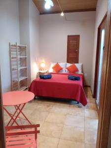 1 dormitorio con 1 cama con manta roja y mesa en LA MAISON OLIVER SPEEDS, en São Miguel do Gostoso