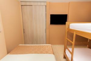 a small room with two bunk beds and a television at Hotel Aixo Suites By GEH Suites in Cartagena de Indias