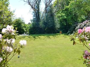 un gran patio de césped con árboles y flores rosas en Flackley Ash Country House Hotel en Rye