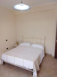 ein weißes Bett in einem weißen Schlafzimmer mit einer Lampe in der Unterkunft Nilu' e Sagio' in Baronissi