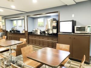a restaurant with tables and chairs and a kitchen at Days Inn & Suites by Wyndham Merrillville in Merrillville