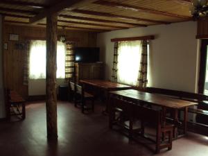 uma sala de jantar com mesas e cadeiras de madeira e janelas em Complex turistic Nora Rau Sadului em Rau Sadului