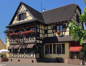 ein schwarzes und gelbes Gebäude mit Blumen auf dem Balkon in der Unterkunft Hôtel-Restaurant A La Couronne in Kilstett