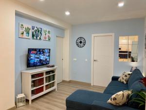 ein Wohnzimmer mit einem blauen Sofa und einem Fernseher in der Unterkunft Lagunillas Voyager Apartment BY NAMASTE ELITE in Málaga