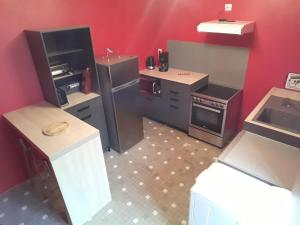 a kitchen with appliances and a red wall at Gîte de la Bigaillonne in Saint-Marcel