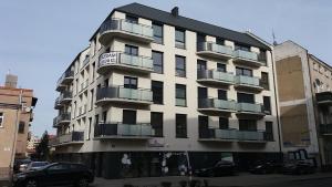 a large white building with balconies on a street at Leszno City Center Apartments in Leszno