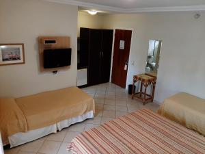 a hotel room with two beds and a television at Hotel Costa Balena, Conforto e Piscina aquecida e coberta a 100m da Praia da Enseada in Guarujá