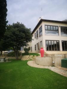 a large white building with a red vase in the yard at Bristow Luxury Suites With Back Up Power and Free Wi-Fi in Roodepoort