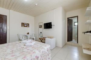 Habitación blanca con cama y TV en Pousada Itapeva, en Torres