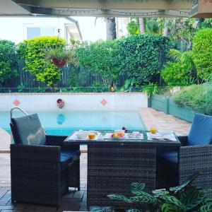 a table and chairs next to a swimming pool at Robyn's Nest - Bed and Breakfast in Tewantin