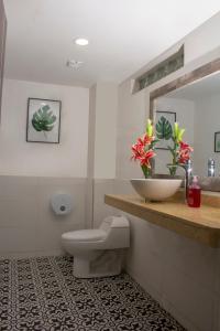 een badkamer met een toilet, een wastafel en een spiegel bij Hotel Avanti Chipichape in Cali