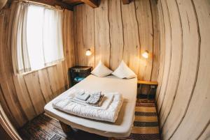 uma cama num chalé de madeira com uma janela em Sunny Nights Homestead Rustic House em Gataučiai