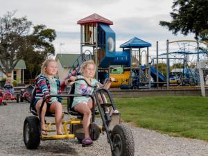 two young girls riding on a toy car at a park at Motueka Apartment in Motueka