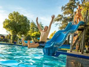 a young boy jumping off a slide in a swimming pool at Motueka Apartment in Motueka