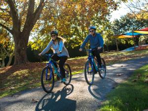 a man and woman riding bikes down a path at Motueka Apartment in Motueka
