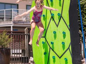 a young girl jumping on a climbing wall at Motueka Apartment in Motueka