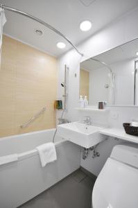 a bathroom with a sink and a tub and a mirror at Mito Keisei Hotel in Mito