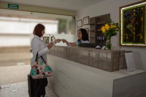 Dwie kobiety stoją przy kasie. w obiekcie Hotel Avanti Chipichape w mieście Cali
