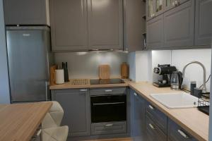 a small kitchen with gray cabinets and a sink at Apartament Soft 16 in Biała Podlaska