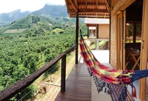 a hammock on the balcony of a house with a view at Pousada Café da Mata in Caparaó Velho