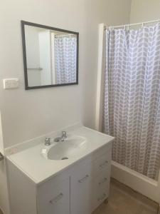 Baño blanco con lavabo y espejo en Tin Can Bay Budget Accommodation, en Tin Can Bay