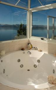 Una bañera en un baño con una ventana grande. en Departamento Costanera, en San Carlos de Bariloche