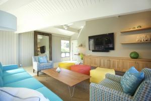 a living room with blue and yellow chairs and a table at Haena Kai home in Haena