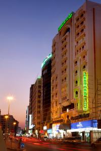 un bâtiment avec des panneaux de néon sur son côté dans l'établissement Landmark Plaza Hotel, à Dubaï