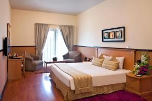 a hotel room with a large bed and a chair at Landmark Plaza Hotel in Dubai