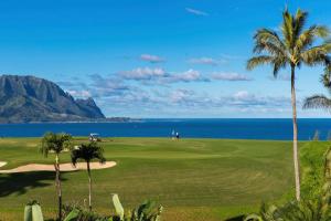 un campo de golf con palmeras y el océano en Hale Moi 112A, King Bed, Kitchen, Washer Dryer, AC, Sunsets condo, en Princeville