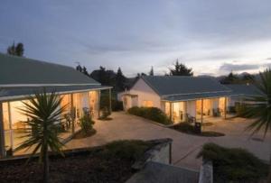 une grande maison éclairée dans une cour dans l'établissement Pauanui Pines Motor Lodge, à Pauanui