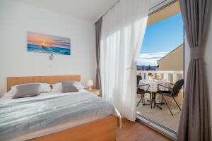 a bedroom with a bed and a balcony with a table at Villa Lelas in Makarska