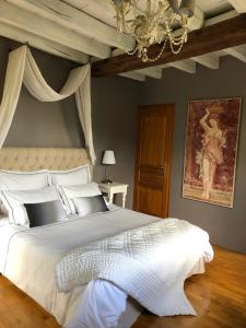 Un dormitorio con una gran cama blanca y una lámpara de araña. en Moulin de la Chevriere, en Saché