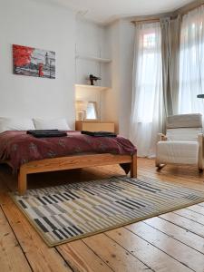 ein Schlafzimmer mit einem Bett, einem Stuhl und einem Teppich in der Unterkunft Home In Queen's Park in London
