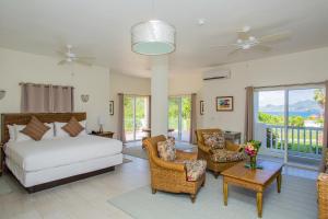 a bedroom with a bed and chairs and a balcony at Mount Nevis Hotel in Nevis