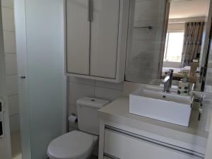 a white bathroom with a toilet and a sink at Ap Sob Medida, Ar Cond, Garagem, Próx praia, Mercados e Farmácias in Itapema +26 photos