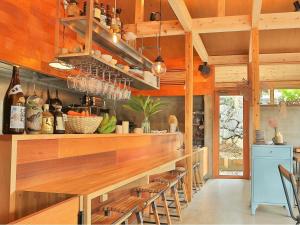 una cocina con barra de madera con taburetes en KAWASEMINOSU (MUKAKA VILLA) en Nago