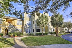a large yellow house with palm trees and a driveway at Modern Condo with Pool 4 Mi to Clearwater Beach! in Clearwater