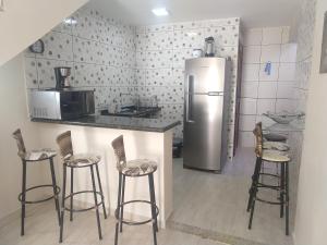 a kitchen with a refrigerator and some bar stools at Triplex na praia do forte in Cabo Frio