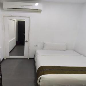 Habitación blanca con 2 camas y puerta en Swiss Hotel Kuala Lumpur, en Kuala Lumpur