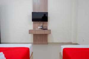 a room with two beds and a flat screen tv at RedDoorz near Pacific Mall Tegal 2 in Tegal +32 photos