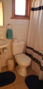 a bathroom with a toilet and a sink and a shower curtain at Cabañas cerca de Valdivia, en San José de la Mariquina in San José de la Mariquina +5 photos