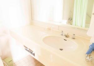 a white bathroom with a sink and a mirror at Irou in Tonosho