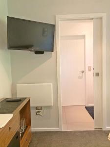 a bathroom with a sink and a tv on the wall at The Garden Studio - Queenstown in Queenstown