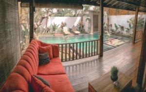a living room with a couch and a swimming pool at Villa Rumah Lumbung The Wooden House in Ubud