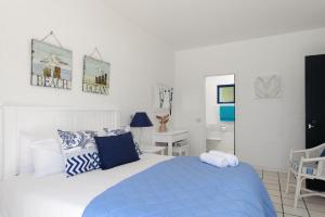 ein weißes Schlafzimmer mit einem blauen Bett und einem Schreibtisch in der Unterkunft Santorini Akrotiri 30 - Family only in Ballito