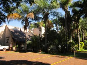 a house with palm trees in front of a parking lot at Lion's Guesthouse and The Buck&Lion Restaurant in Groblersdal